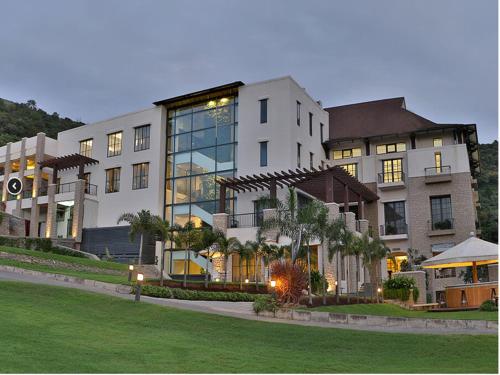 a large white building with a lawn in front of it at Oxford Golf Resort in Pune
