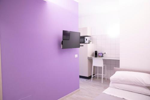 a room with a purple wall with a bed and a table at Marigold Residence in Roseto degli Abruzzi