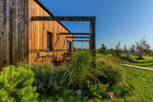 a wooden barn with a table and chairs in a field at Pod Mazurskim Niebem boho in Piecki