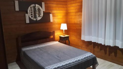 um quarto com uma cama e um candeeiro sobre uma mesa em Casa Aconchegante Praia do Rosa Ibiraquera SC em Imbituba