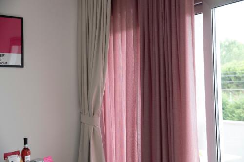 a room with a window with a pink curtain at Marigold Residence in Roseto degli Abruzzi