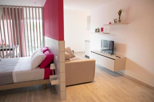 a bedroom with a bed and a couch and a tv at Marigold Residence in Roseto degli Abruzzi
