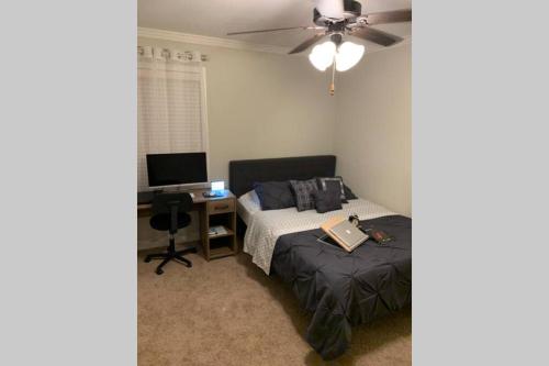 a bedroom with a bed and a desk with a laptop on it at Peaceful 3BR/2BA Hidden Lake Home Near ACOM w/WiFi in Dothan