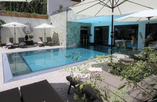 a pool with chairs and umbrellas next to a building at Das Naturjuwel in Fiss