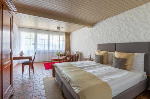 Schlafzimmer mit einem Bett, einem Tisch und einem Schreibtisch in der Unterkunft Swiss-Chalet Merlischachen - Romantik Schloss-Hotel am See in Küssnacht