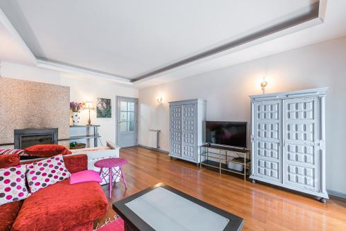 a living room with a red couch and a tv at Praça Guest House in Arouca
