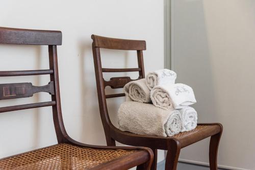 a stack of towels on a wooden chair at Praça Guest House in Arouca