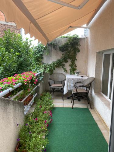 a patio with a table and some flowers and a green carpet at Apartments Skadarlija in Belgrade