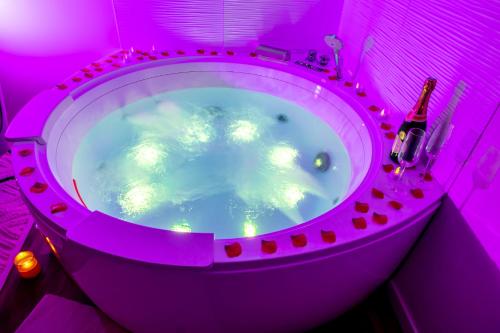 eine lila Badewanne mit einer Flasche Wein und ein Aquarium in der Unterkunft LoveSparadise -Suite Le Secret in Saints