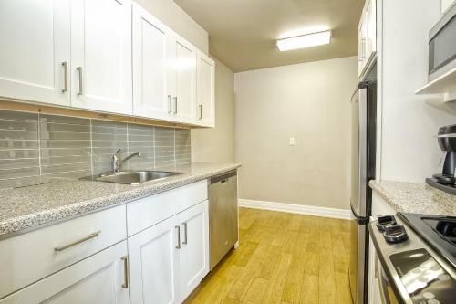 a kitchen with white cabinets and a stainless steel refrigerator at Town Inn Suites Hotel in Toronto