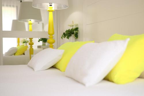 a white bed with yellow and white pillows on it at Le relais d'Angélique in Lunel