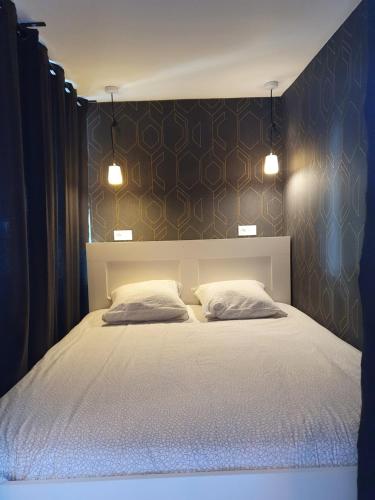 a bedroom with a large bed with two pillows at Appartement Pierres de Loire- Linge inclus -1er étage in La Bohalle