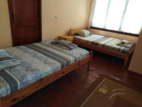 Habitación con 2 camas, suelo de madera y ventanas. en Къща Рачеви, en Tryavna