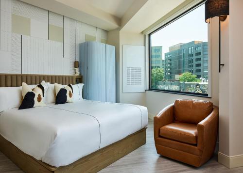 a bedroom with a bed and a chair and a window at Catbird Hotel in Denver
