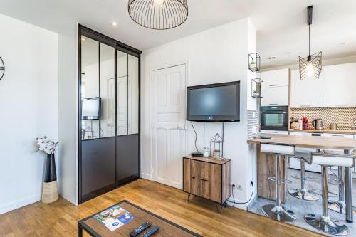 uma sala de estar com uma mesa e uma televisão e uma cozinha em Appartement "Le Preize" - Centre ville - Garage privé em Troyes
