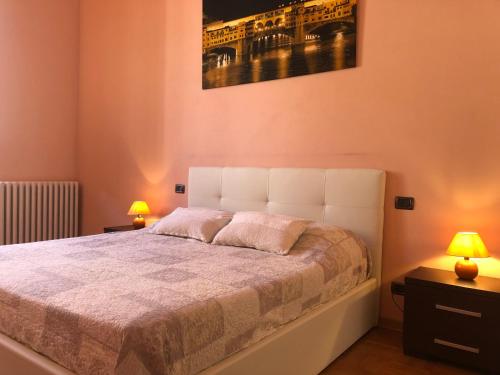 a bedroom with a large bed with two lamps at 3 Perle all'Accademia Apartments in Florence