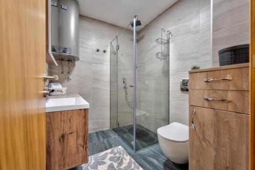 a bathroom with a shower and a toilet and a sink at Apartman Enjoy in Zlatibor