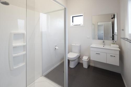 a white bathroom with a toilet and a glass shower at Cass Crib - Lake Tekapo in Lake Tekapo