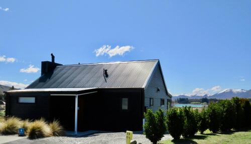 a black barn with a man on the roof at Cass Crib - Lake Tekapo in Lake Tekapo