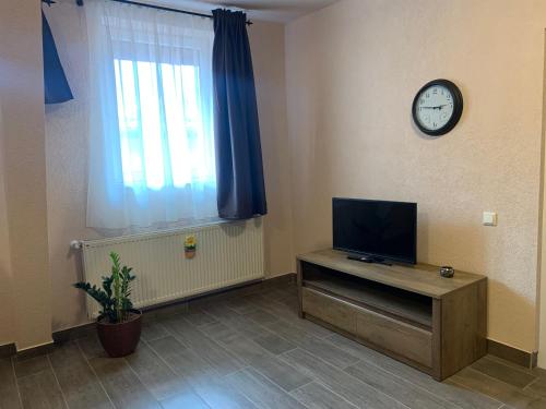 a living room with a tv and a clock on the wall at Braun Residence in Săcele