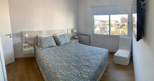 een slaapkamer met een bed met een blauw dekbed en een raam bij MH Buona Vista in Monte Hermoso