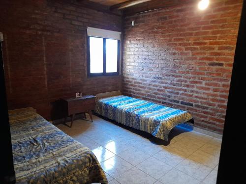 Pokój z 2 łóżkami i ceglaną ścianą w obiekcie Sol del Este w mieście Alto de Sierra