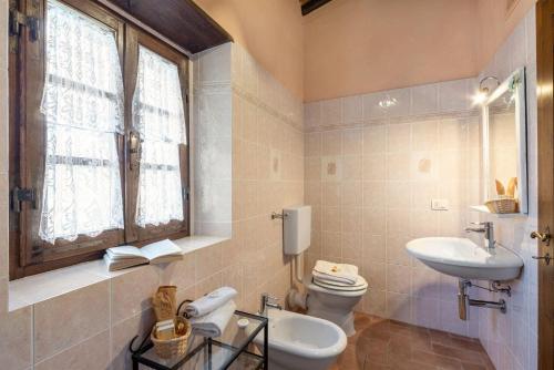 uma casa de banho com um lavatório, um WC e uma janela. em Uva em Radda in Chianti