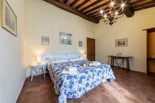 um quarto com uma cama azul e branca e duas mesas em Uva em Radda in Chianti