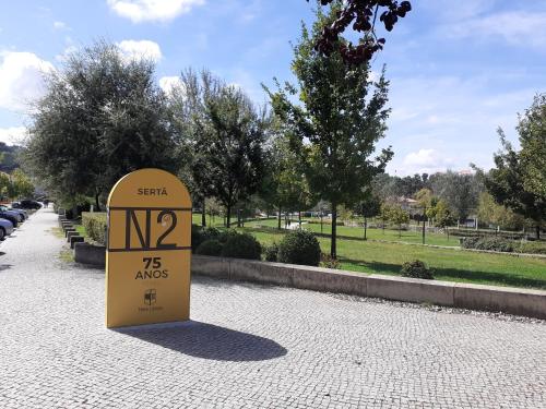 a yellow sign on a sidewalk in a park at Hostel Sertã in Sertã