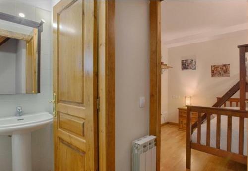 baño con lavabo, espejo y puerta en Apartamento caleta, en Les