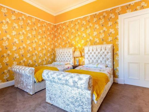 two beds in a room with yellow wallpaper at North Bank House in Lybster