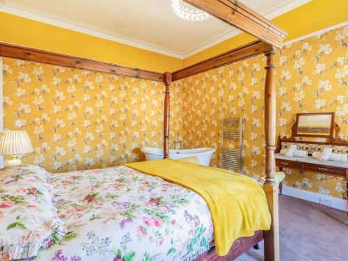 a bedroom with a canopy bed and yellow wallpaper at North Bank House in Lybster