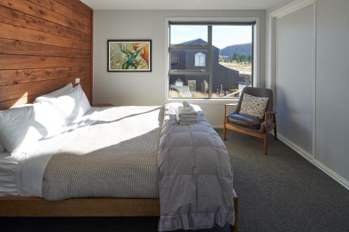 a bedroom with a bed and a chair and a window at Bivouac - Lake Tekapo in Lake Tekapo