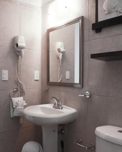 a bathroom with a sink and a mirror and a toilet at Villa Isla Dorada in Isla Mujeres