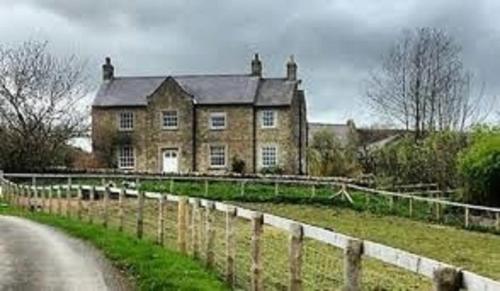 an old house with a fence in front of a road at Low Gingerfield Farm B&B in Richmond