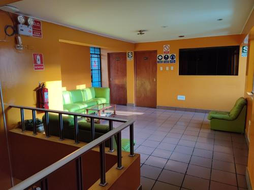 una sala de espera con sillas verdes y TV en Krusty Hostel B&B, en Huaraz