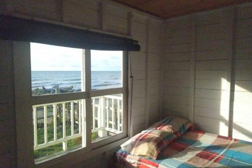 um quarto com uma cama e uma janela com vista para o oceano em La Casa Amarilla (Sobre las playas del mar Caribe) em San Bernardo del Viento