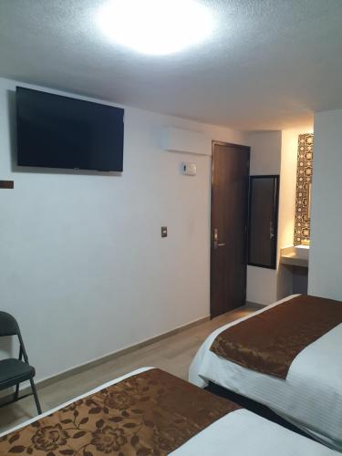 a hotel room with two beds and a flat screen tv at Hotel Don Carlos in Morelia