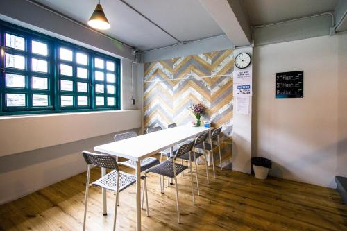 a table and chairs in a room with a clock on a wall at Busket Hostel in Chiang Rai