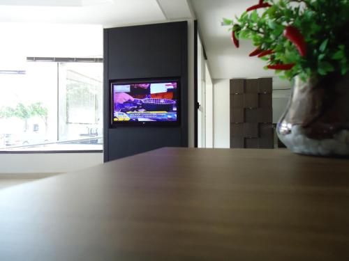 a table with a vase with a tv in a room at Hotel Barril in Primavera do Leste
