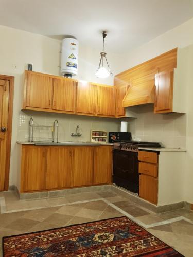 a kitchen with wooden cabinets and a black stove at Entire Apartment 2bed Condo at Burban Oakwood in Bhurban