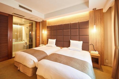 two beds in a hotel room with a bathroom at Pacific Hotel Okinawa in Naha