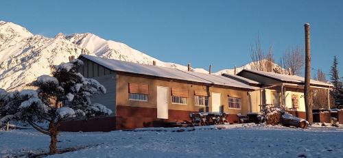 a building in the snow with a mountain in the background at Cabañas Nubes del Plata in Potrerillos