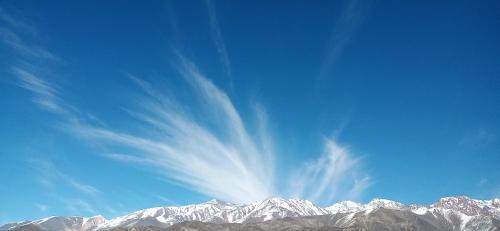 a view of a snow covered mountain under a blue sky at Cabañas Nubes del Plata in Potrerillos