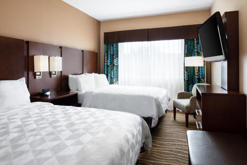 a hotel room with two beds and a flat screen tv at Holiday Inn Hotel & Suites Overland Park-West by IHG in Overland Park