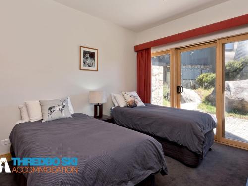 two beds in a room with a window at Ice Chalet 2 in Thredbo