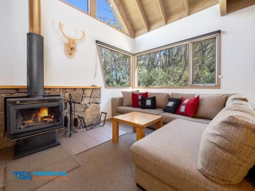 a living room with a couch and a fireplace at Indi Chalet in Thredbo