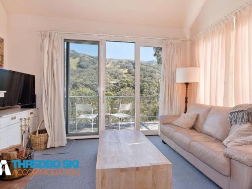 a living room with a couch and a large window at Kaella in Thredbo