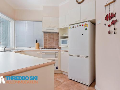 a kitchen with white appliances and a white refrigerator at Kaella in Thredbo