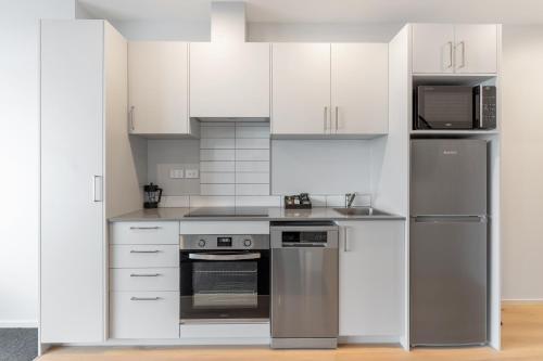 a kitchen with white cabinets and stainless steel appliances at Ramada by Wyndham Newmarket Auckland in Auckland